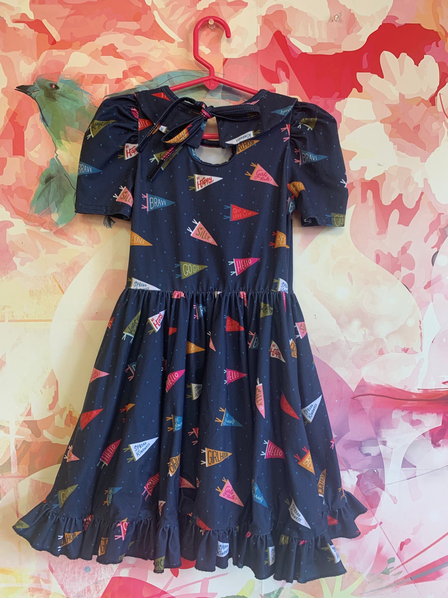 girlhood blue short sleeve dress with positive affirmation pennants. Peter Pan collar, full flowy skirt & keyhole tie at back of neck. Size 4/5T.