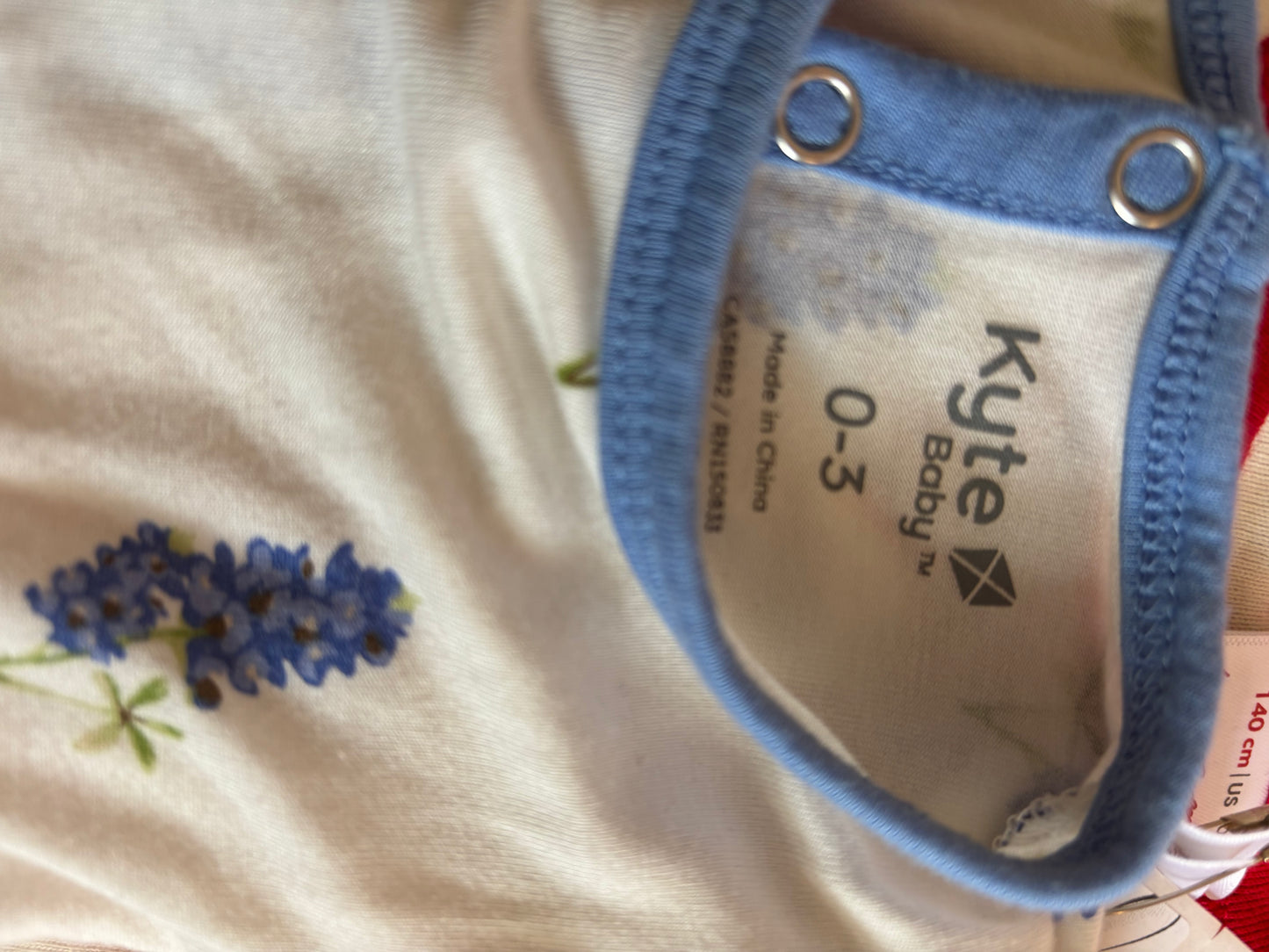 Kyte Baby white dress onesie with blue flowers and blue headband. Made of Bamboo size 0-3m NB