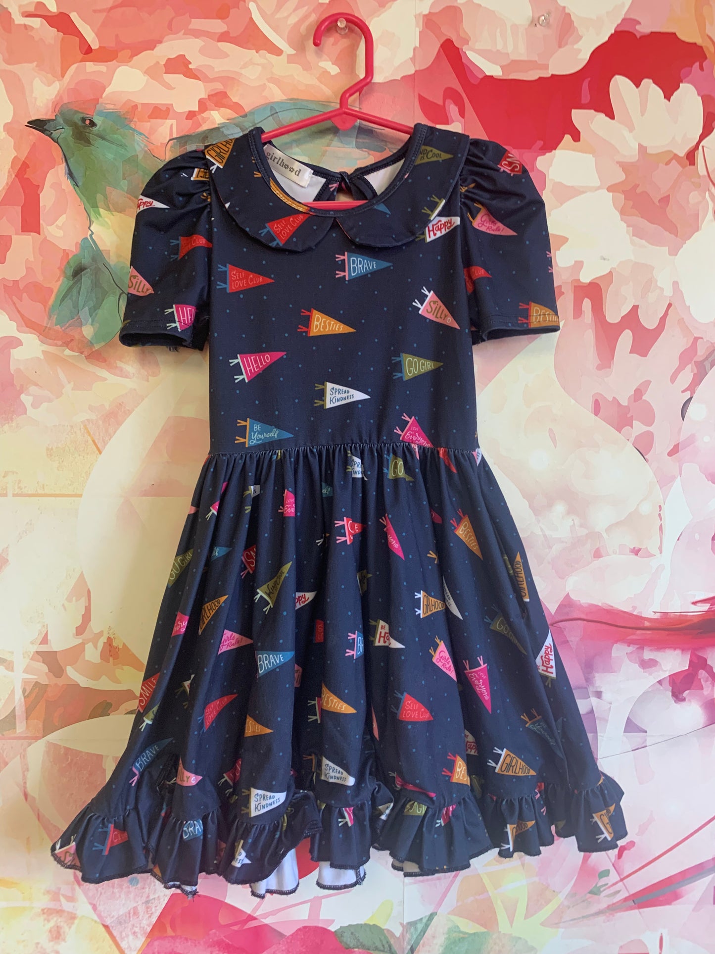 girlhood blue short sleeve dress with positive affirmation pennants. Peter Pan collar, full flowy skirt & keyhole tie at back of neck. Size 4/5T