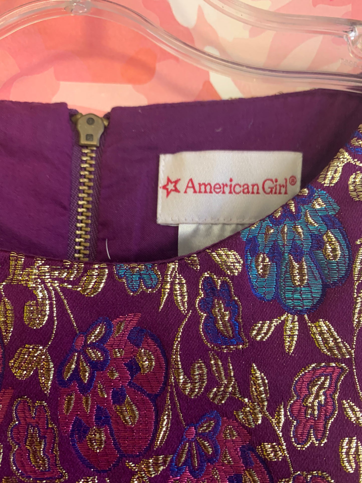 American Girl purple shirt sleeve dress with gold, pink, blue, red sparkly flowers & blue satin waist tie. Zipper closure in back. Size 6