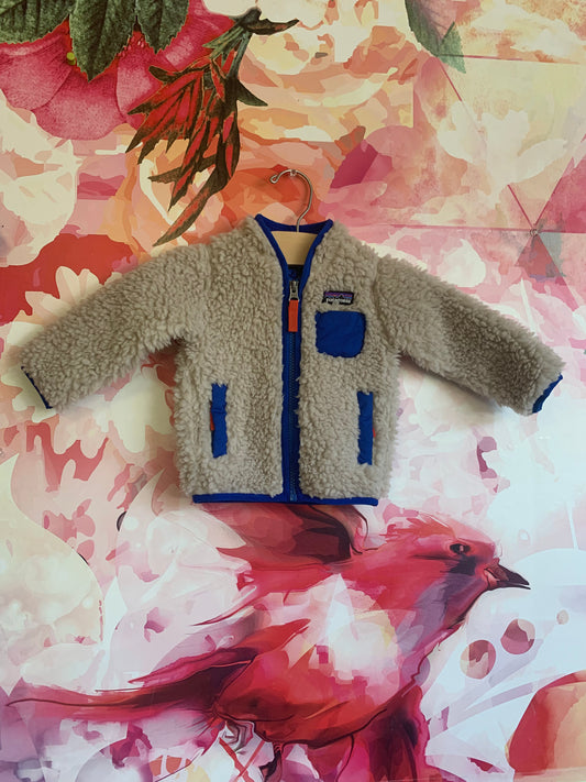 Patagonia Baby Retro-X Fleece Jacket. Natural & blue. Windproof warmth with soft 100% recycled polyester 1/2” pile fleece. Size 3-6m